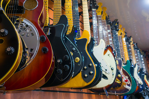 Different electric guitars hang in the music instruments store